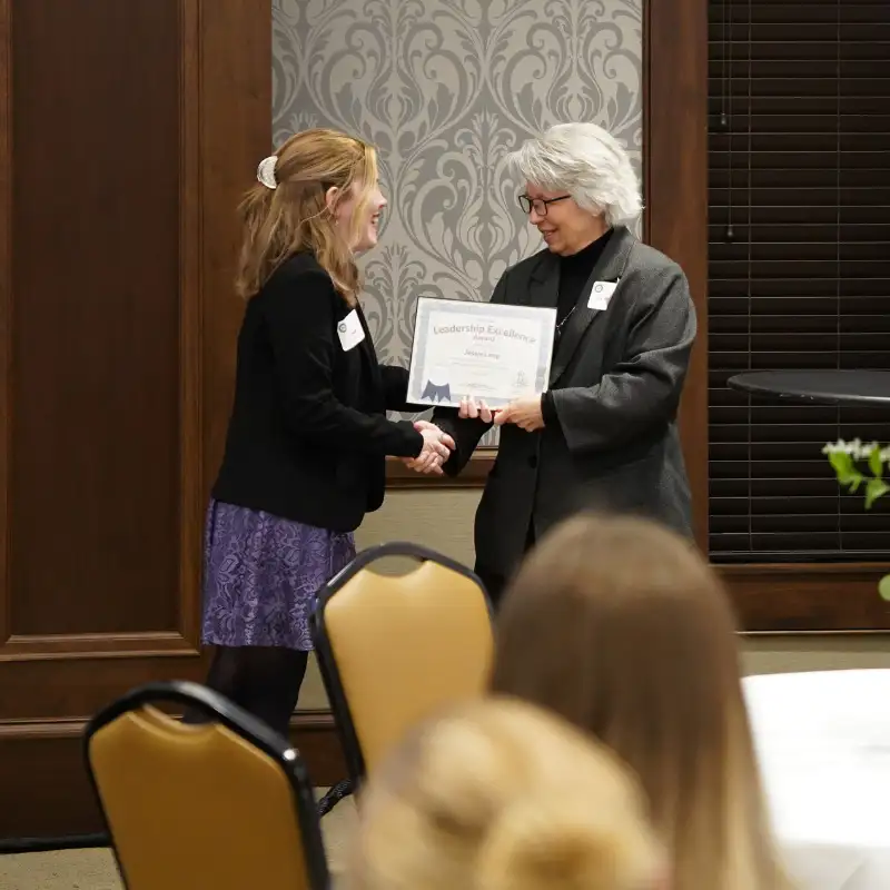 2 people shaking hands as one of them receives a certificate