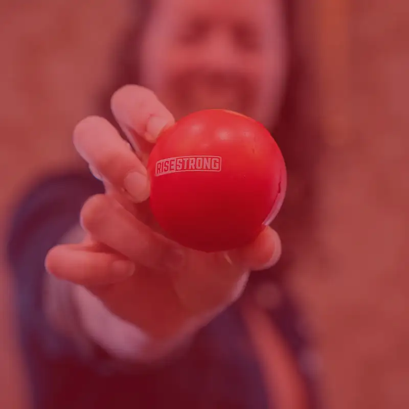 Person holding a red ball that says rise strong toward the camera
