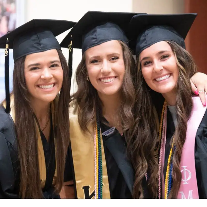 3 graduates posing together in their caps and gowns 