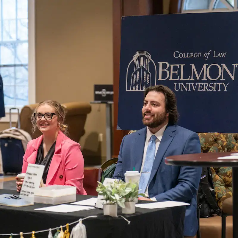 Belmont law students sitting in font of a college of law sign at the law symposium