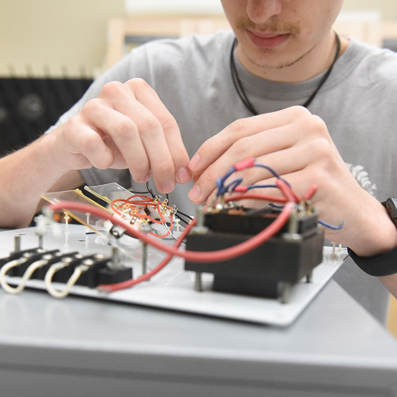 A student attaches wires to a computer board.