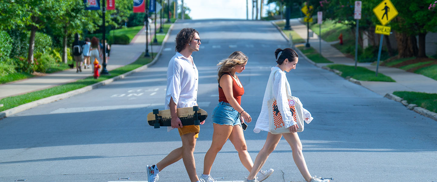 Three students walking across a street at a crosswalk