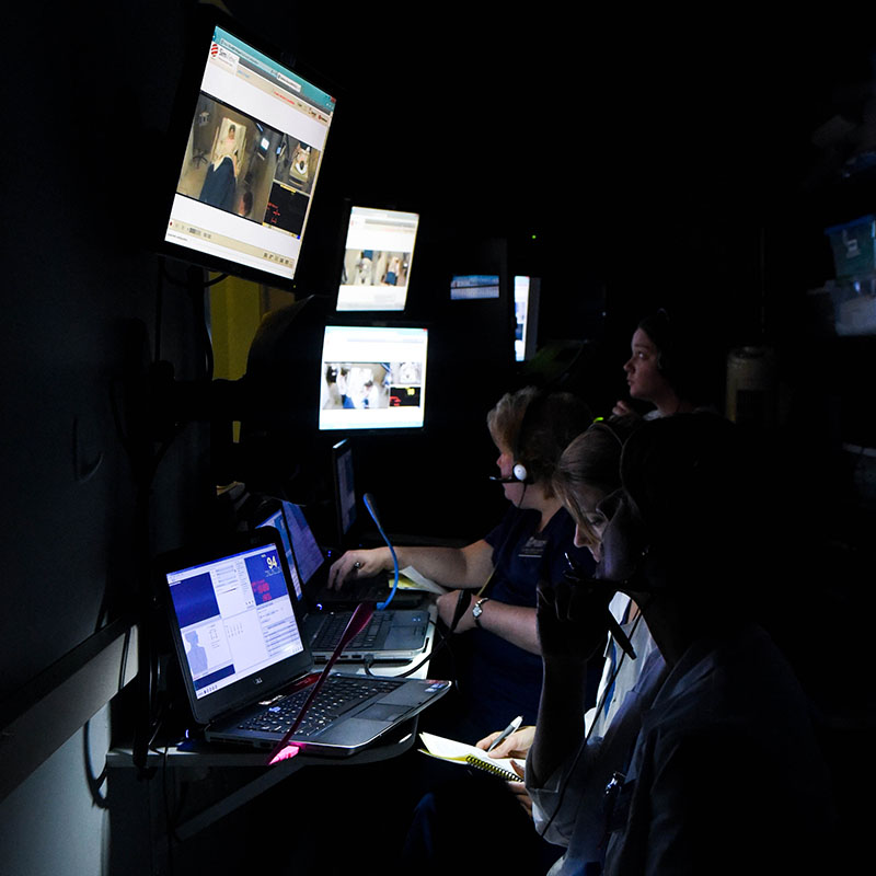 A professor monitors students during a simulation