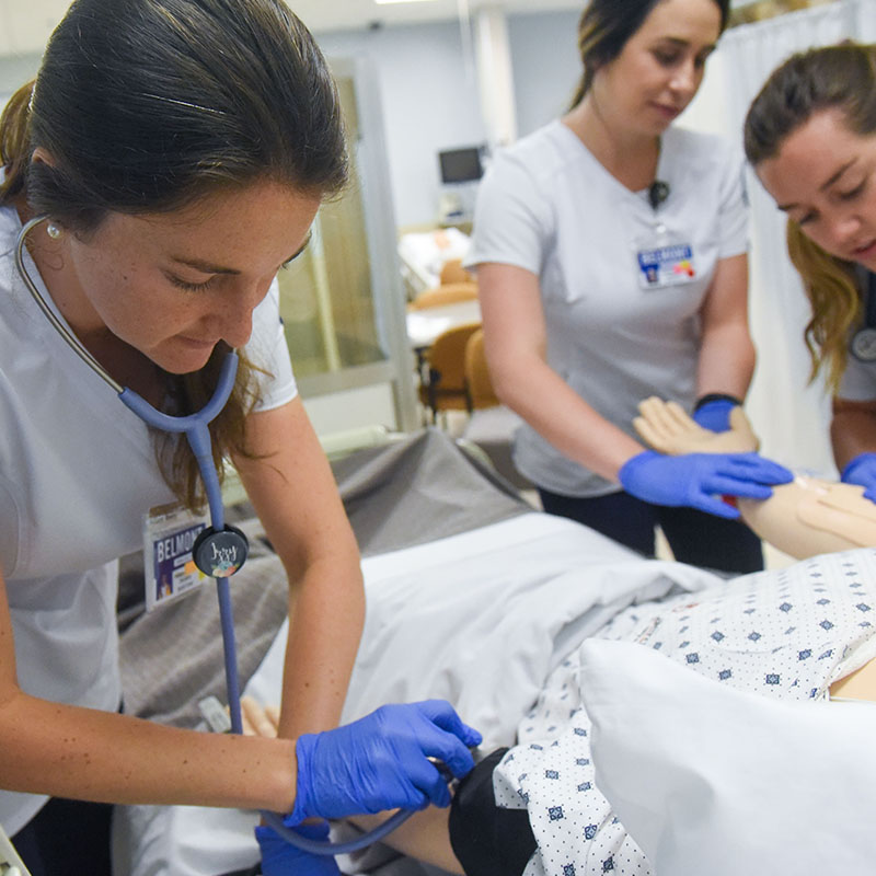 Three Inman College of Nursing students checking the pulse of a manikin.