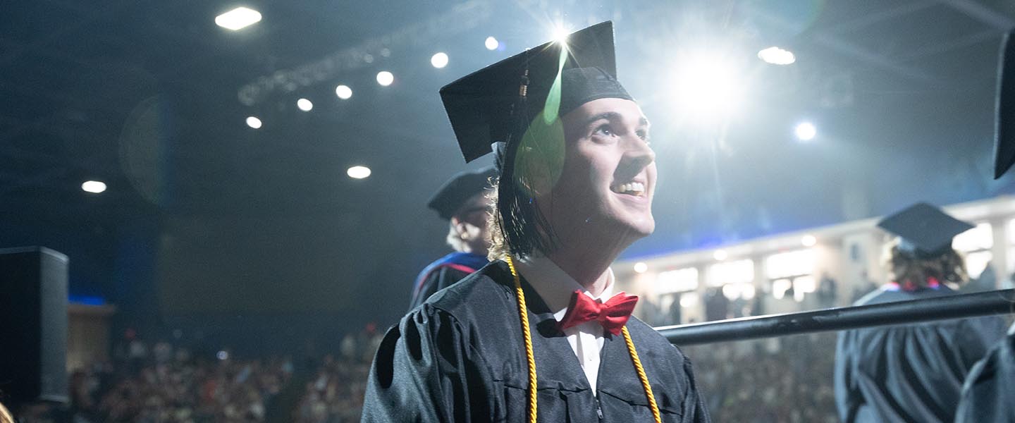 A student at graduation looking up with a smile on his face