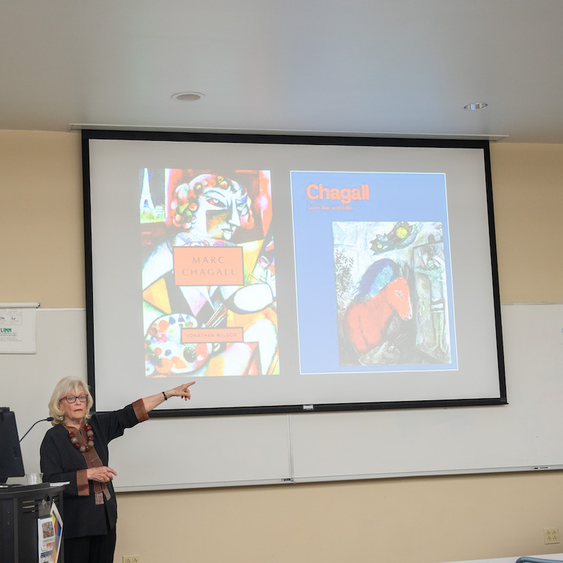 Sandra Bowden presenting in front of a projector showing Chagall art