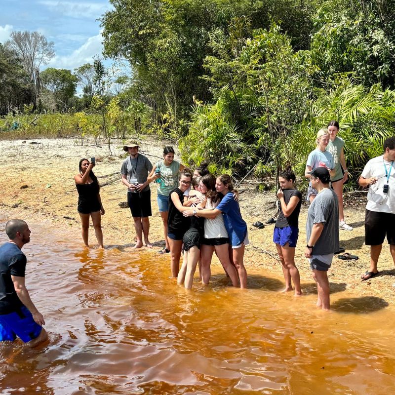 Belmont students getting baptized in the Amazon River