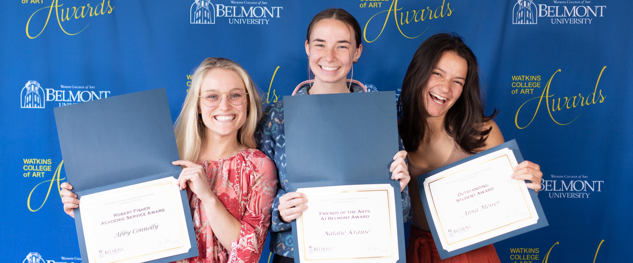 3 art student holding certificates at the watkins college of art awards ceremony