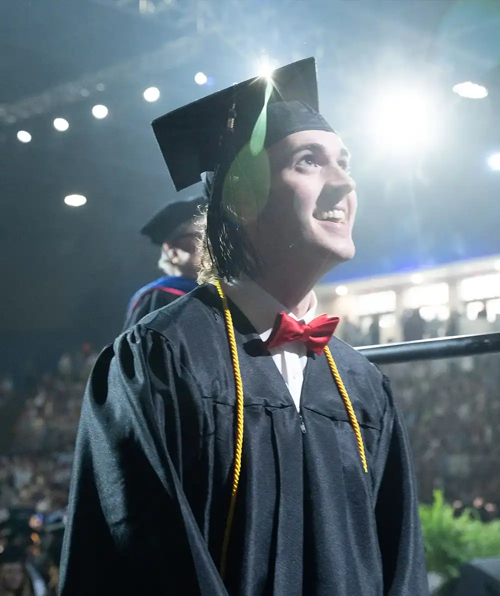 A student at graduation looking up with a smile on his face