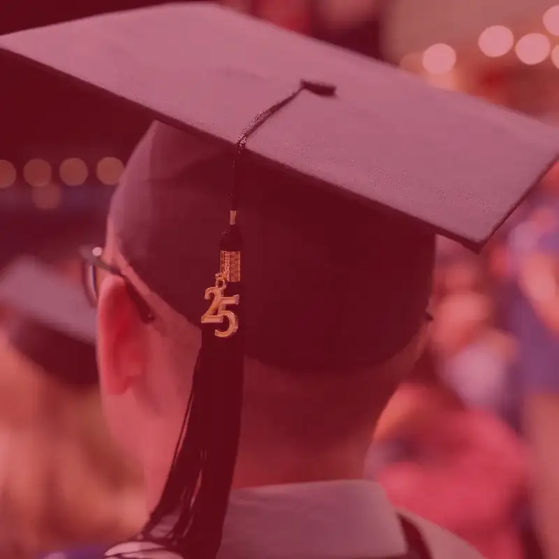A portrait of the back of a male student's head, wearing a black graduate's mortar board with a black tassel adorned with a gold "25" for Class of 2025 
