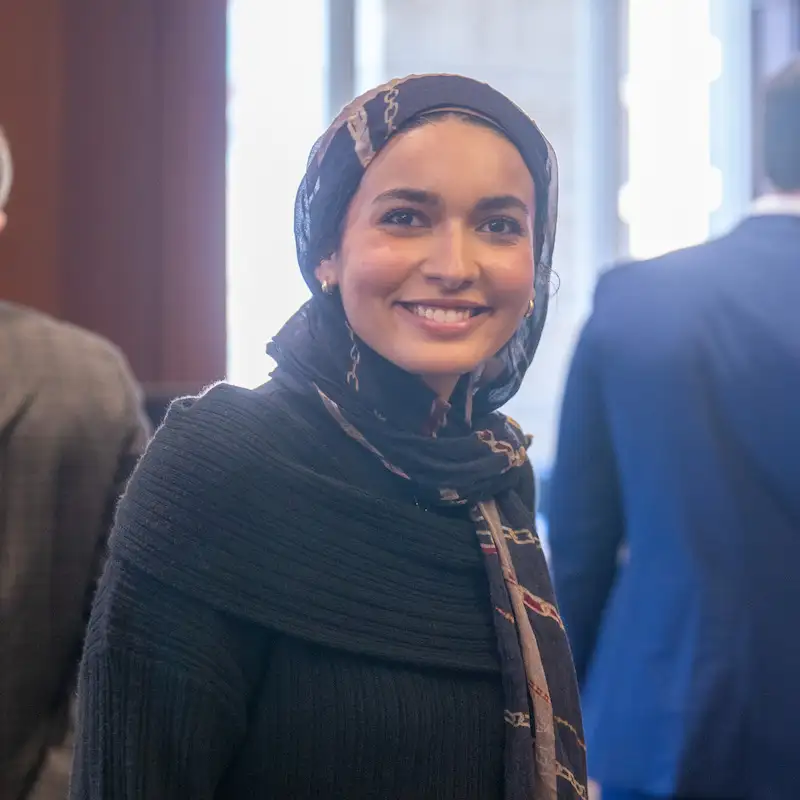 An indoor image of a woman wearing a hair scarf and candidly posing and smiling.