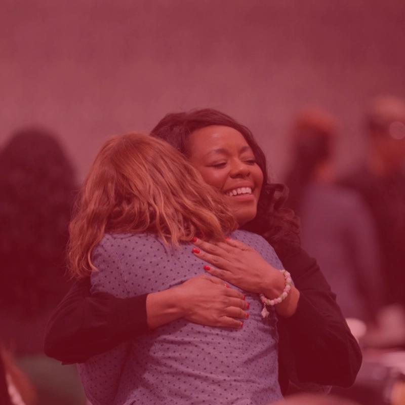Women hug at In Her Honor luncheon