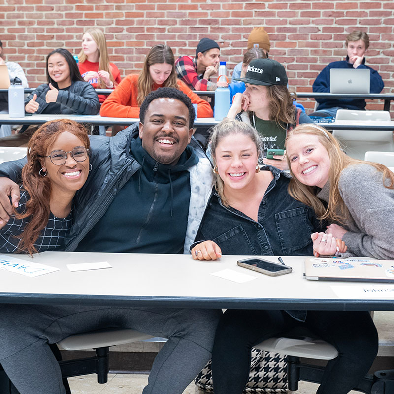 A diverse group of students hugging and smiling before class