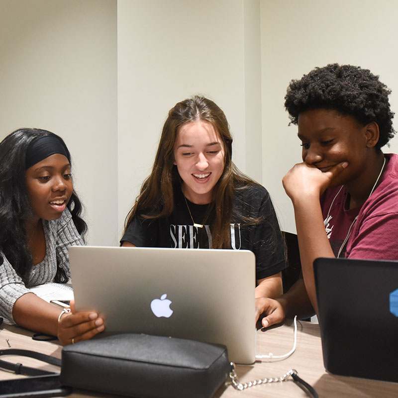 Three students working at a laptop together