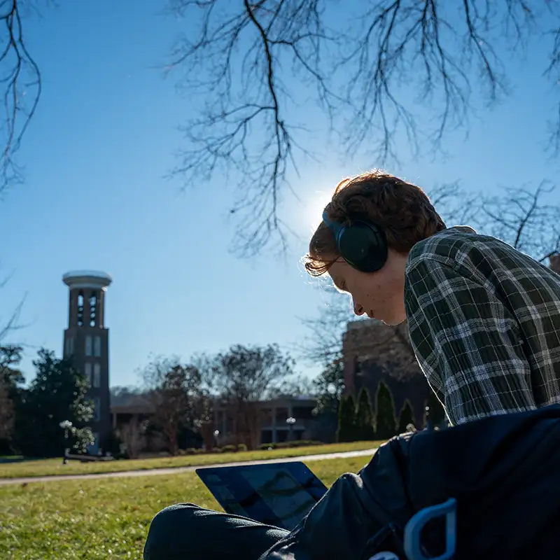 student studying on historic lawn on a sunny day
