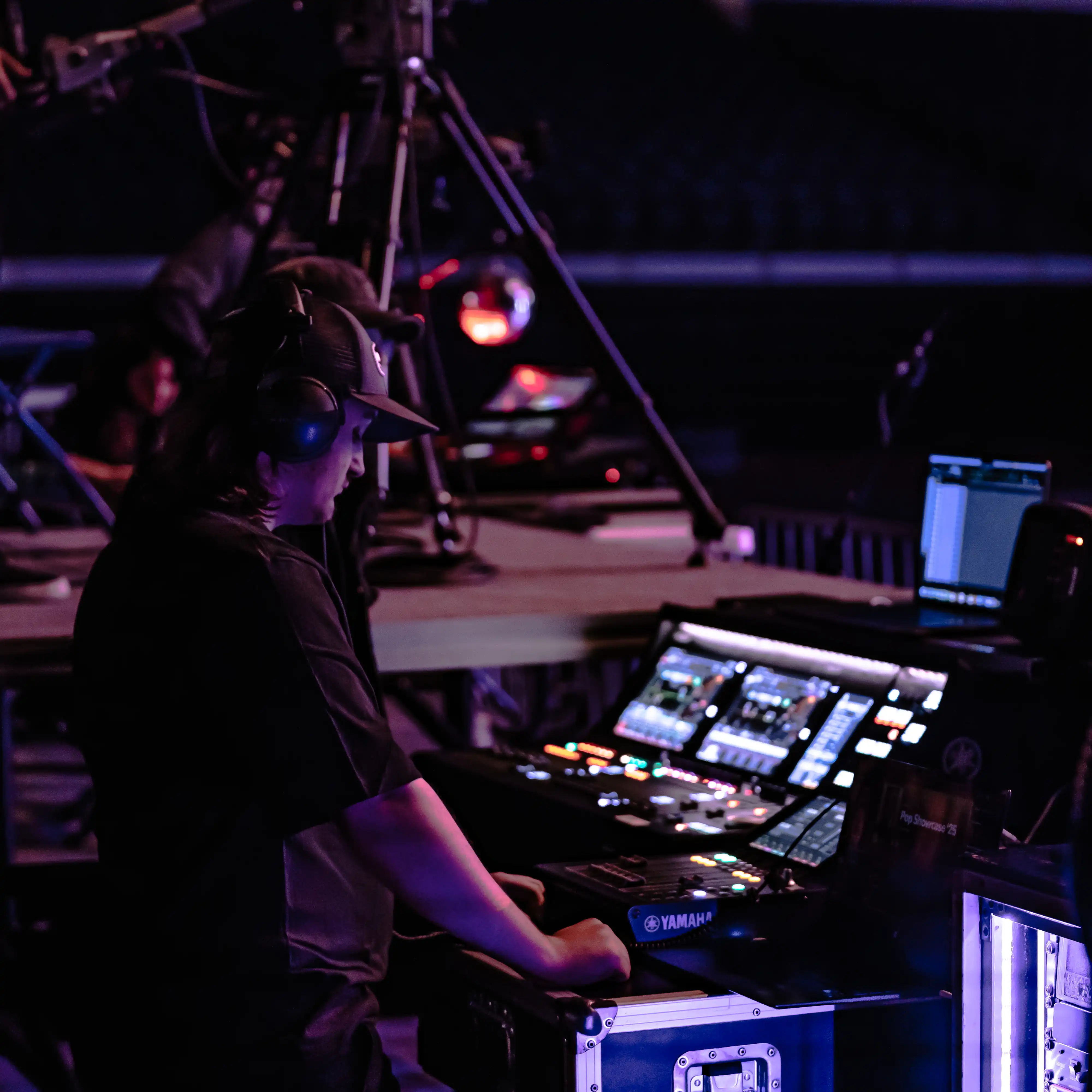 Student operates a professional Yamaha live sound console backstage during a performance, gaining hands-on production experience