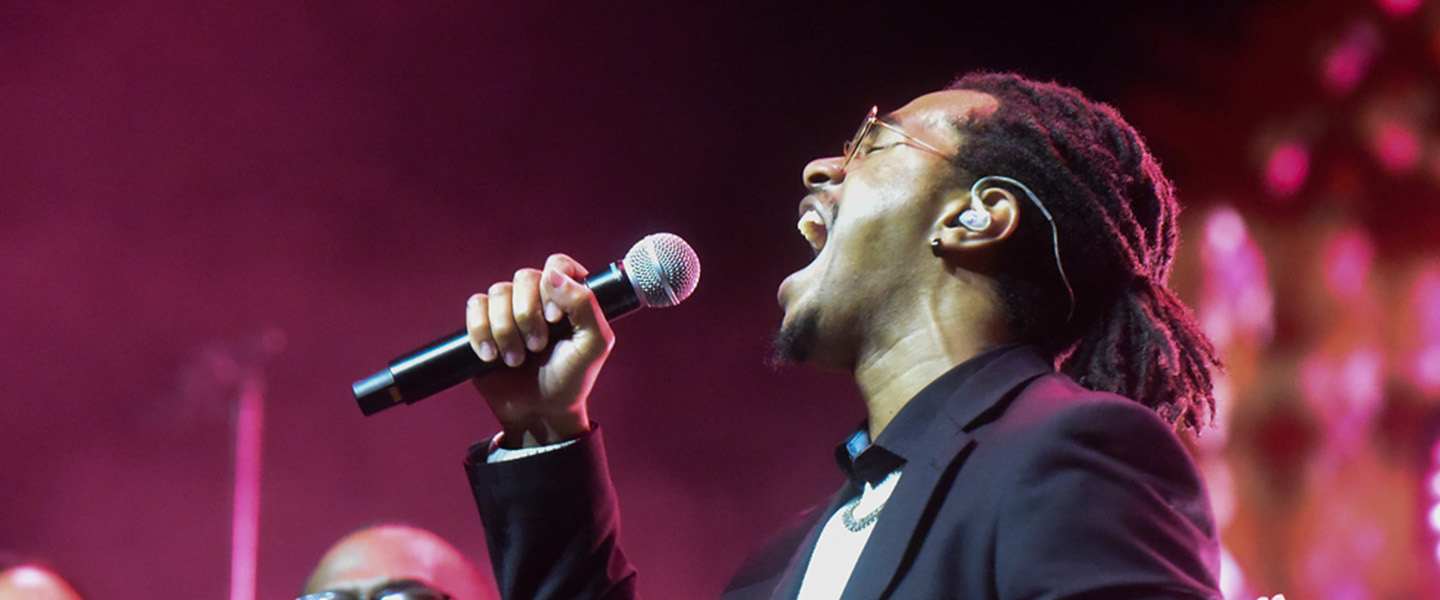 A male student raises a microphone and sings with a lot of energy.