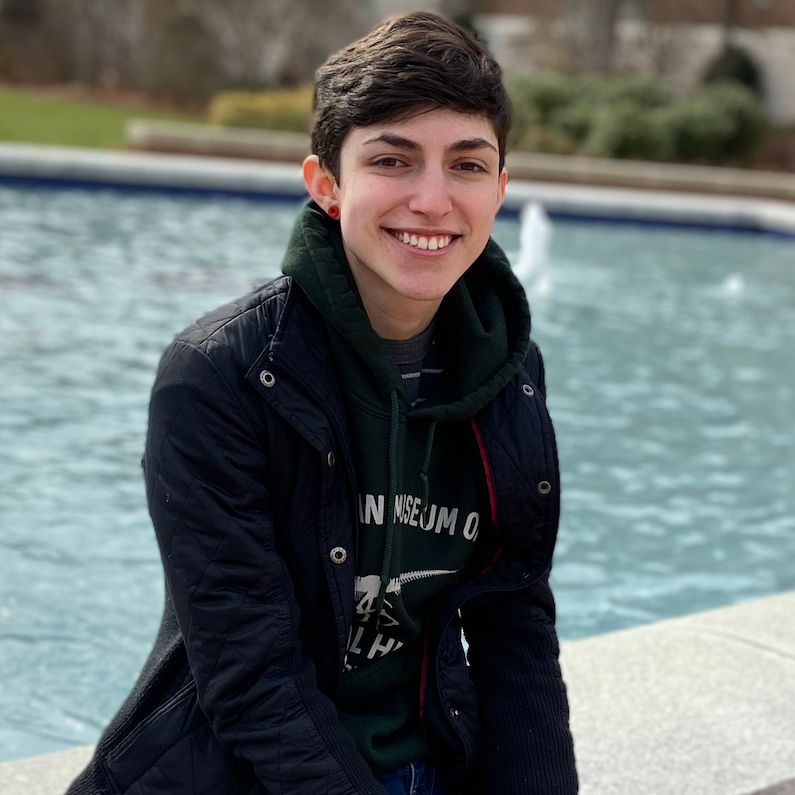 Design Communications graduate Sam Giamundo sits in front of a fountain