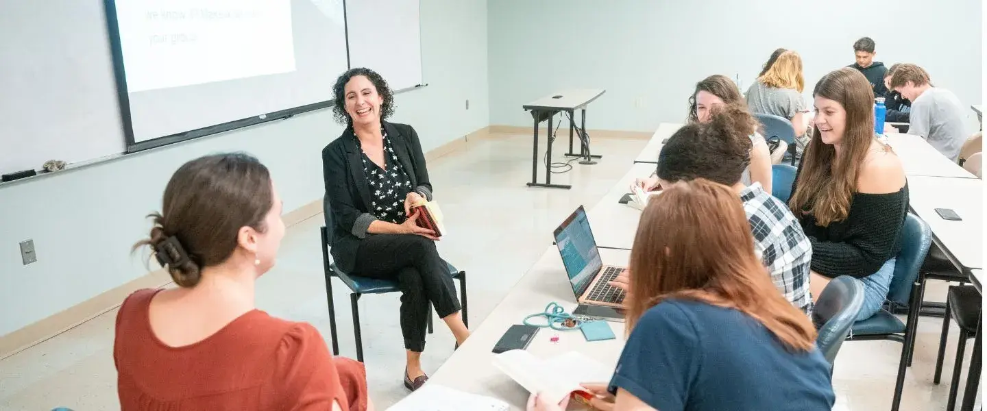 english professor, holding book and have discussion with students