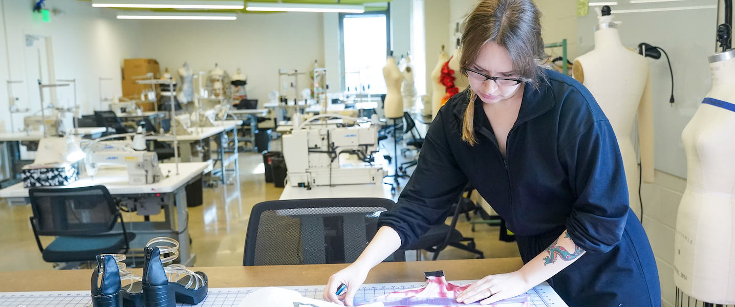 Fashion design student measuring a garment at a table