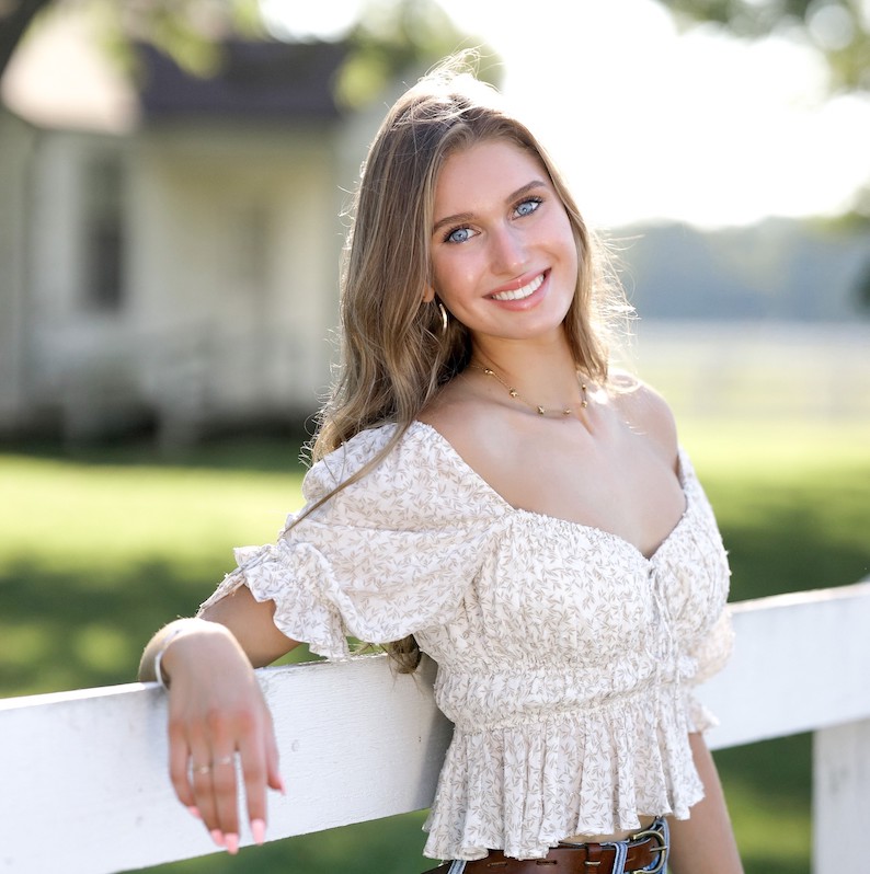 O'More student Laura Finley Hasenbank leaning on a white fence