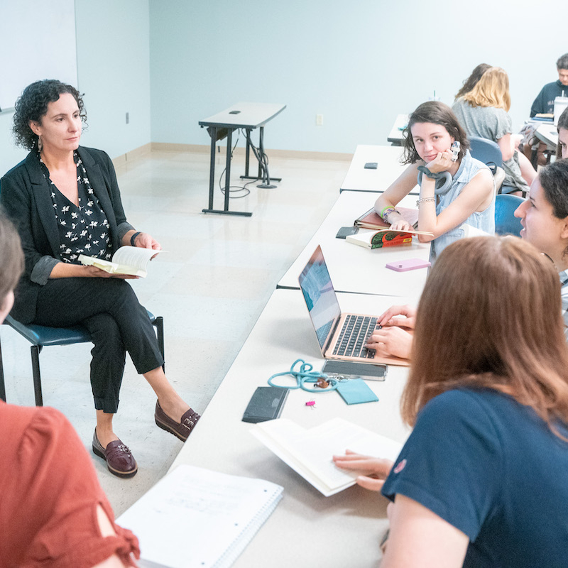 Professor and students have small group discussion in class room