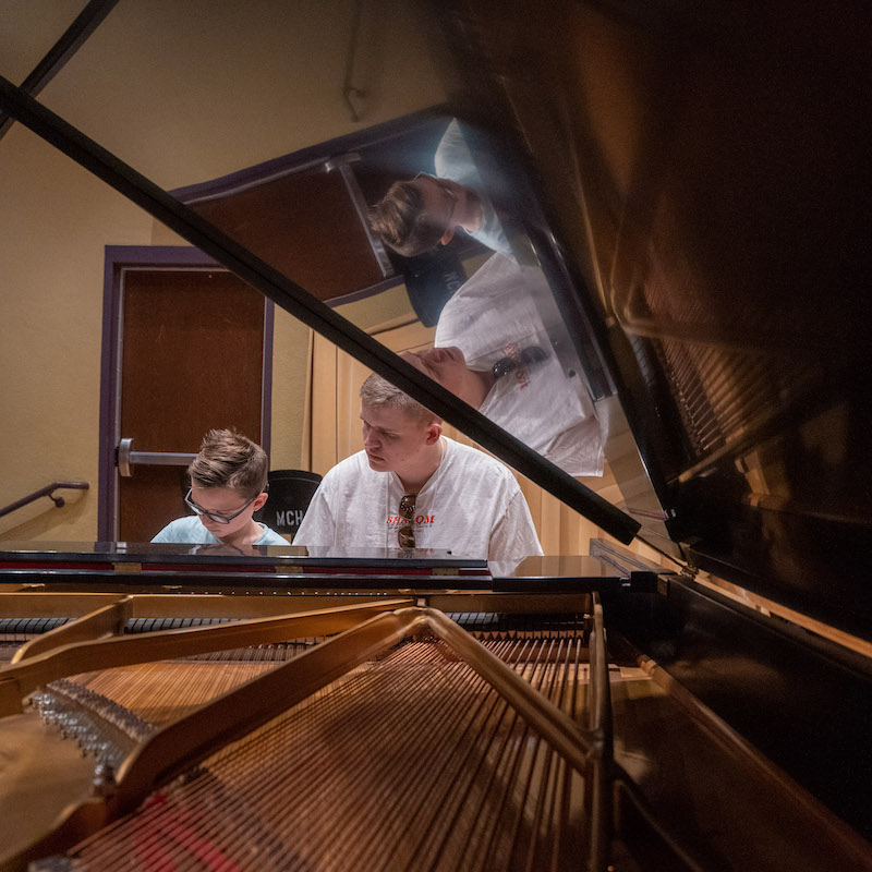 adult teaching a child to play the piano