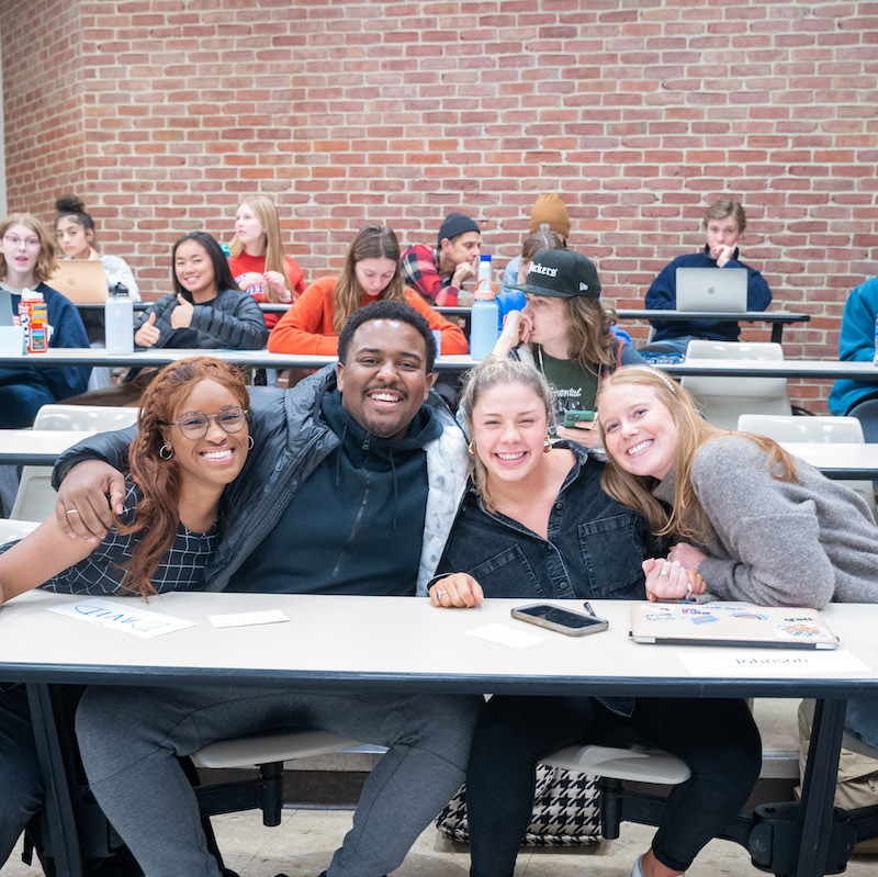 Students posing for picture at desks in class room