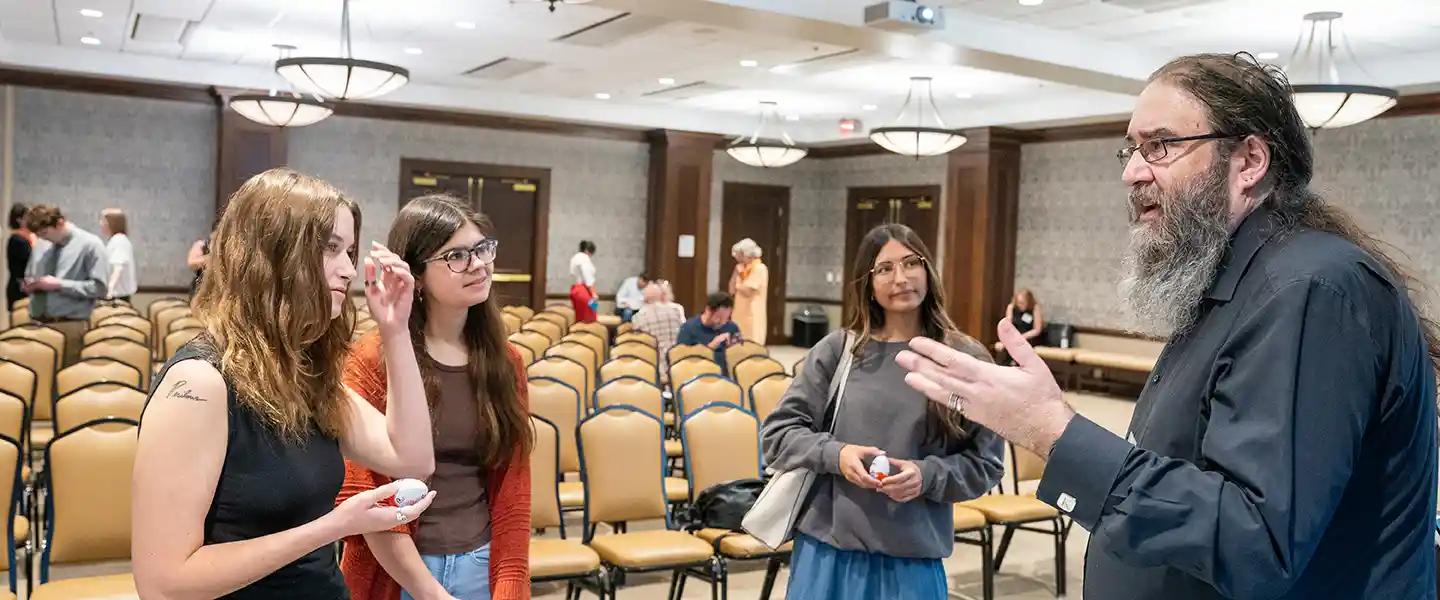 Five students with their arms around each other in the Bunch Multimedia Hall