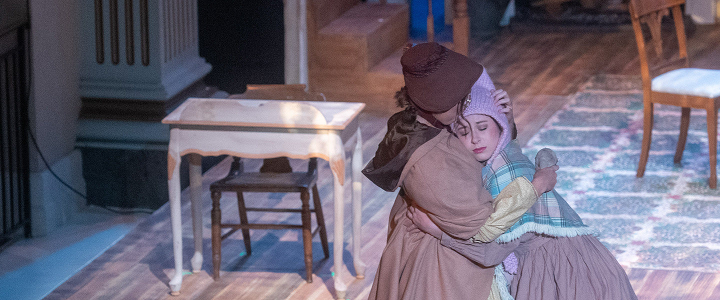 Two female students hug while performing the play, Little Women.