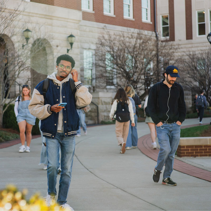 A group of three students walking through Belmont's campus on the way to class