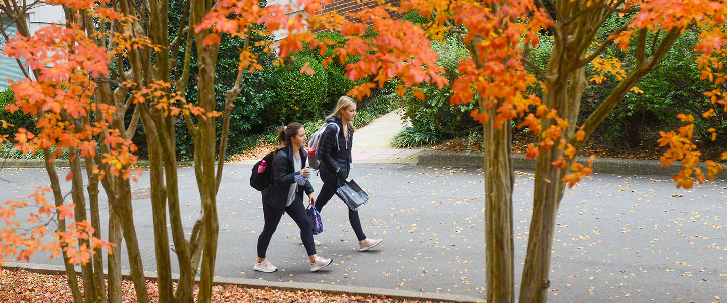 Two students walking through campus on a fall day