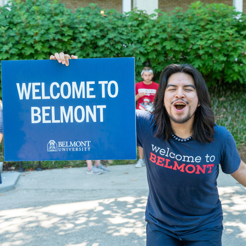 A male student holding a sign that says Welcome to Belmont