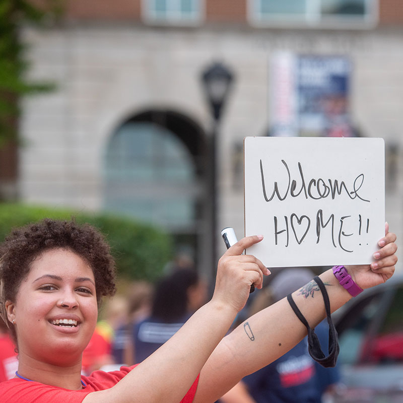 A student holding a sign that says Welcome to Belmont during Move In Day