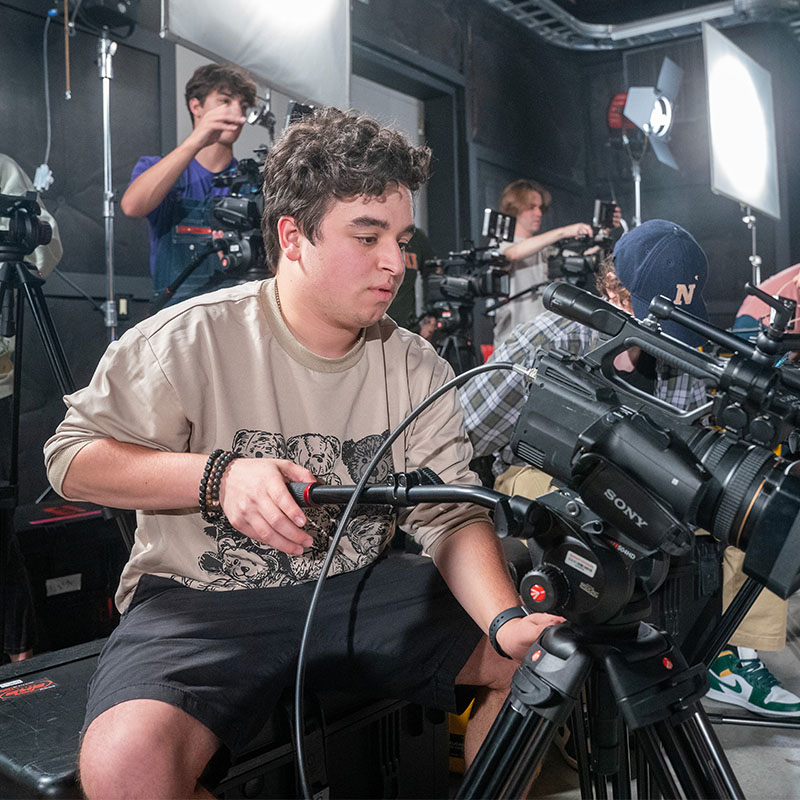Student setting up a camera for a video shoot in Belmont's sound stage