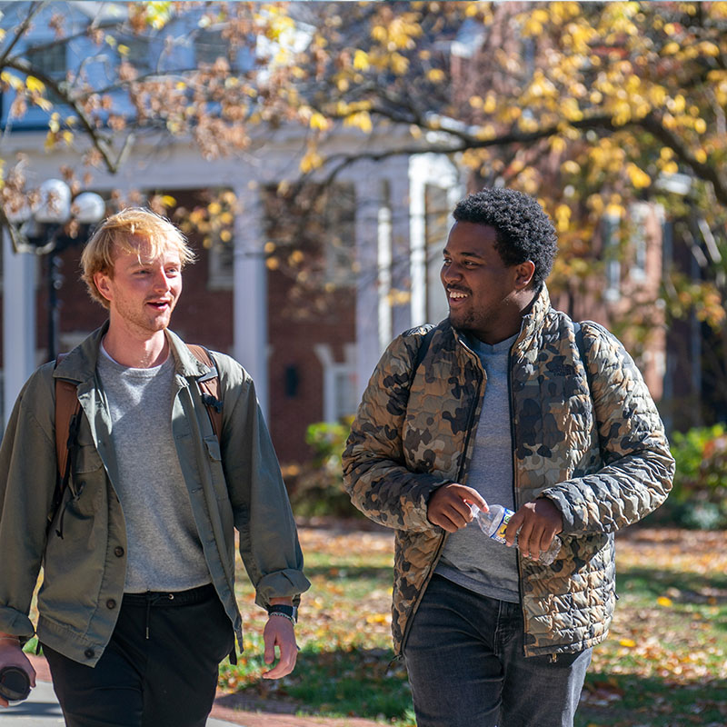 Two male students walking across campus in the fall