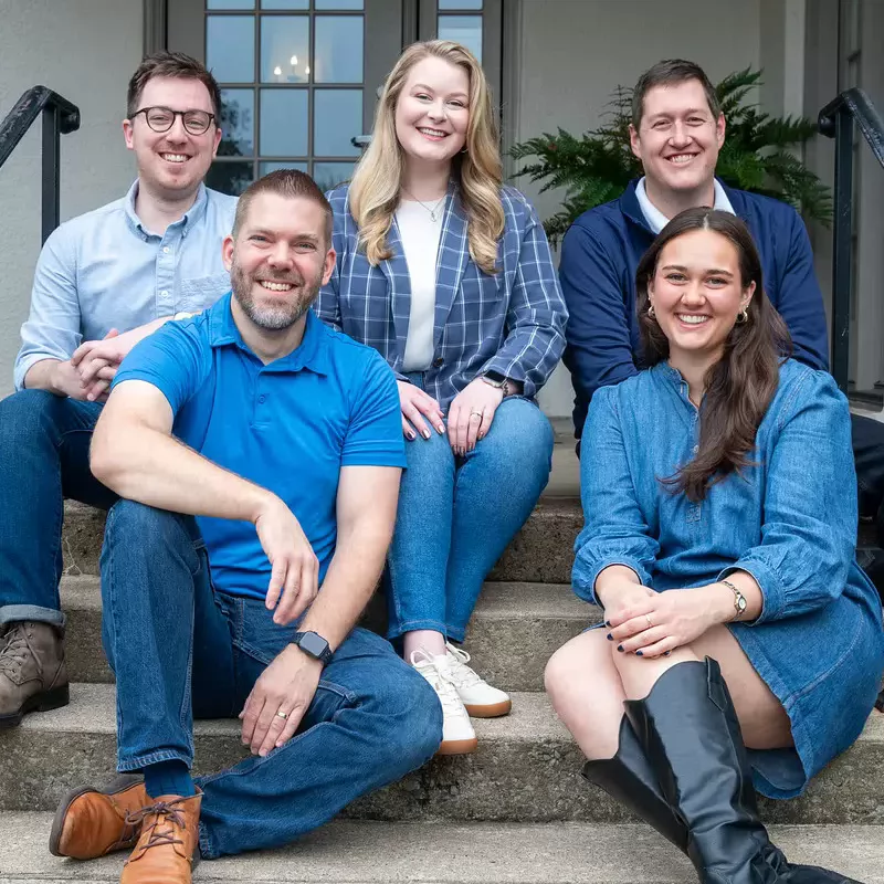 Alumni Engagement Team sitting on the steps of the Foutch Alumni House