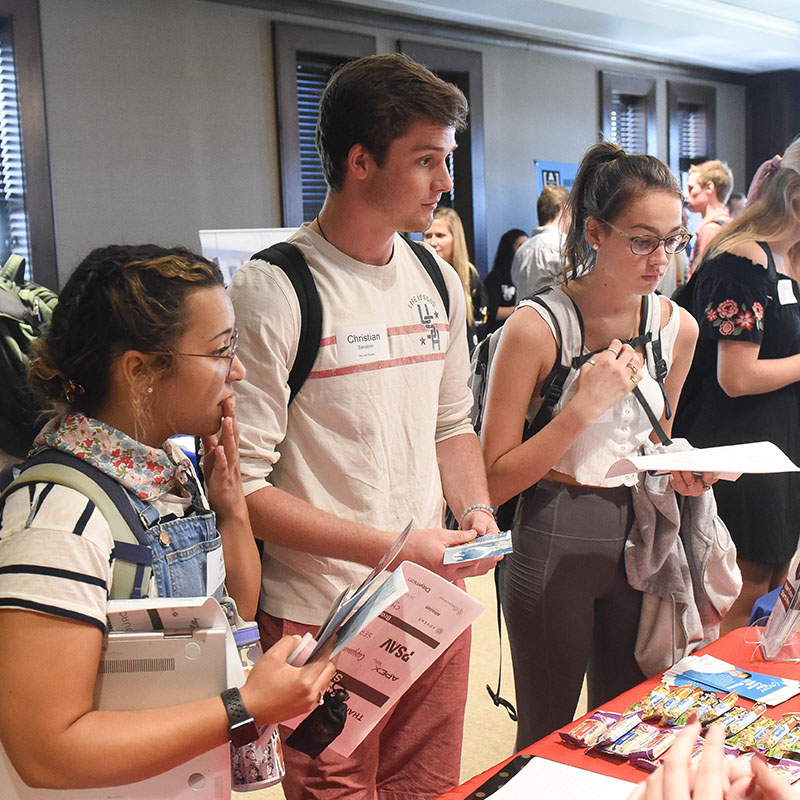 Three students talking to a prospective employer at a career fair