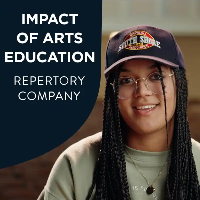 Rue Bradfield wearing glasses, and a baseball cap sits in an auditorium, wearing a sage green sweatshirt with a relaxed, welcoming expression, with the text "Impact Of Arts Education Repertory Company".
