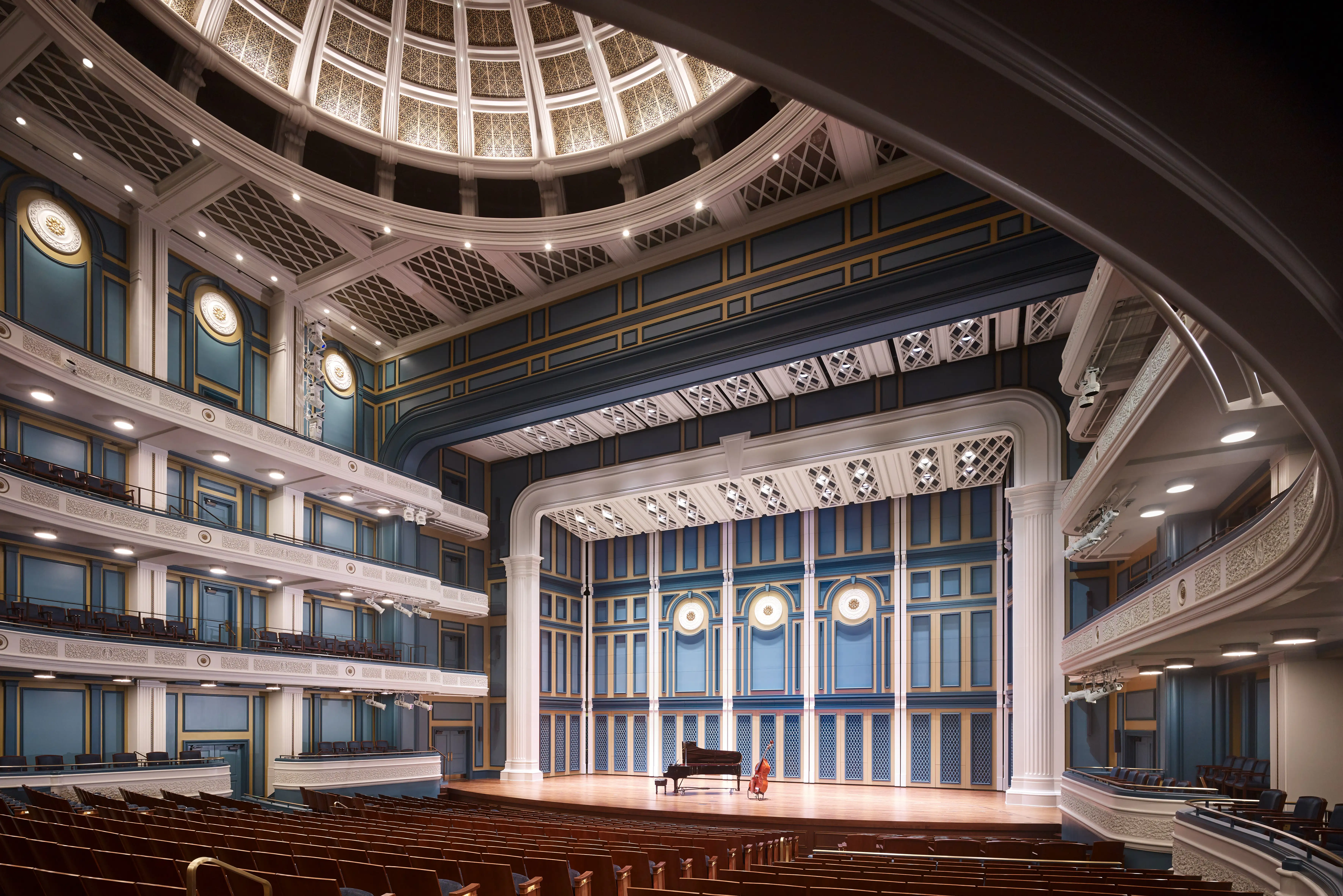 Interior of the Fisher Center for the Performing Arts, showcasing a grand piano on stage beneath a domed ceiling and ornate blue-and-gold detailing.