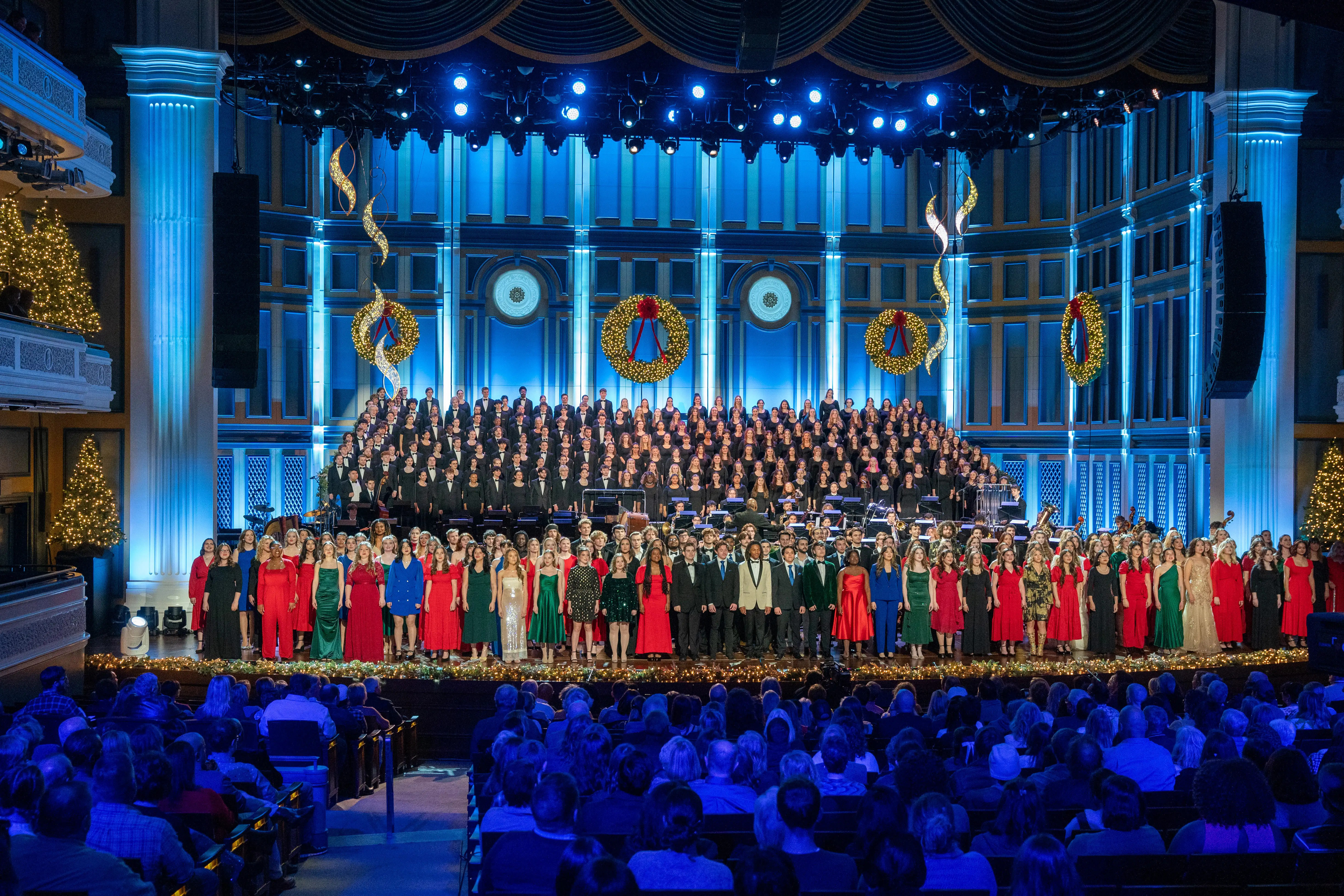 Christmas at Belmont performance at the Fisher Center, featuring a large choir and ensemble in festive attire on a brightly lit, decorated stage.