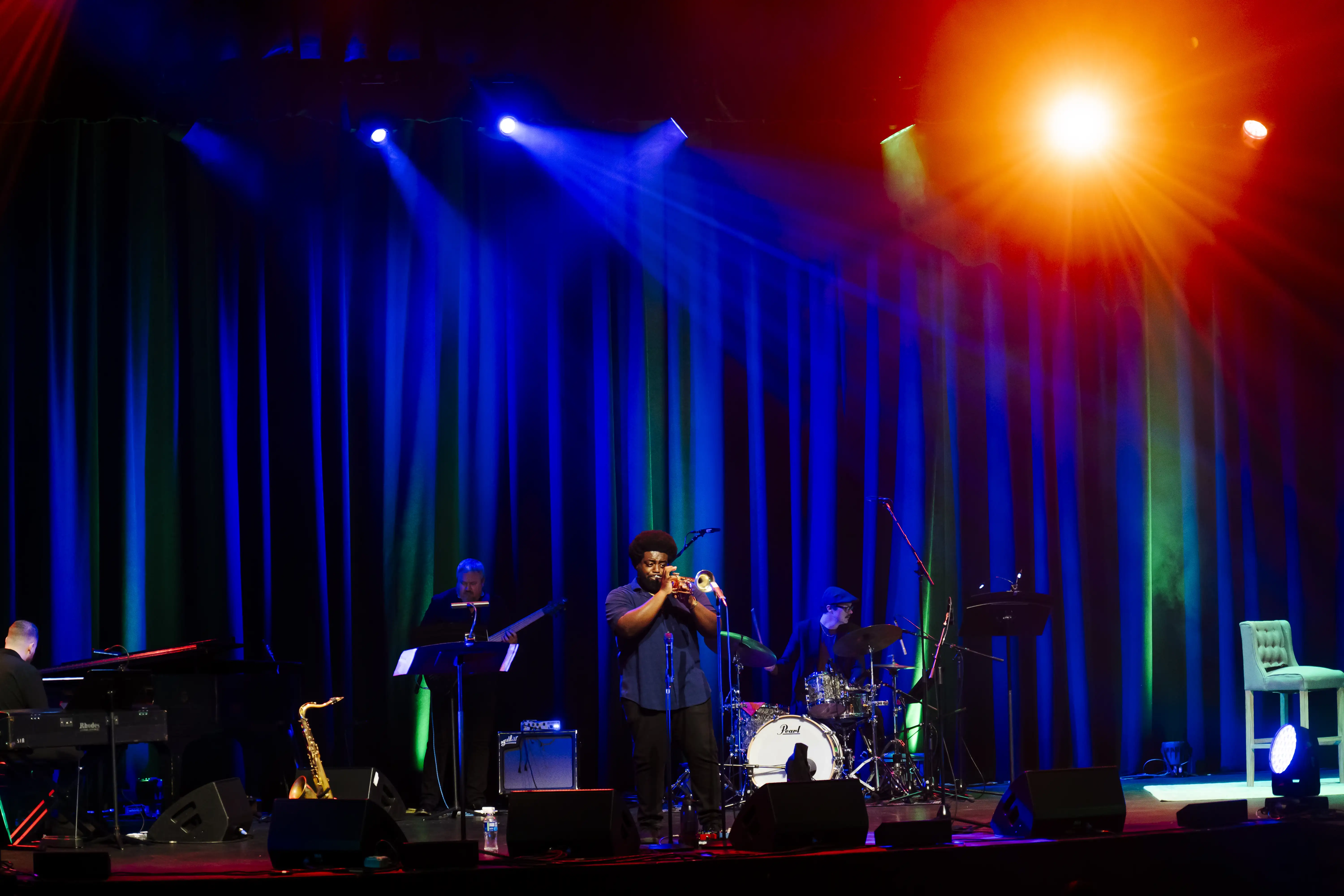 Jazz ensemble performs under colorful lighting onstage in Massey Concert Hall, featuring trumpet, piano, drums, and saxophone.