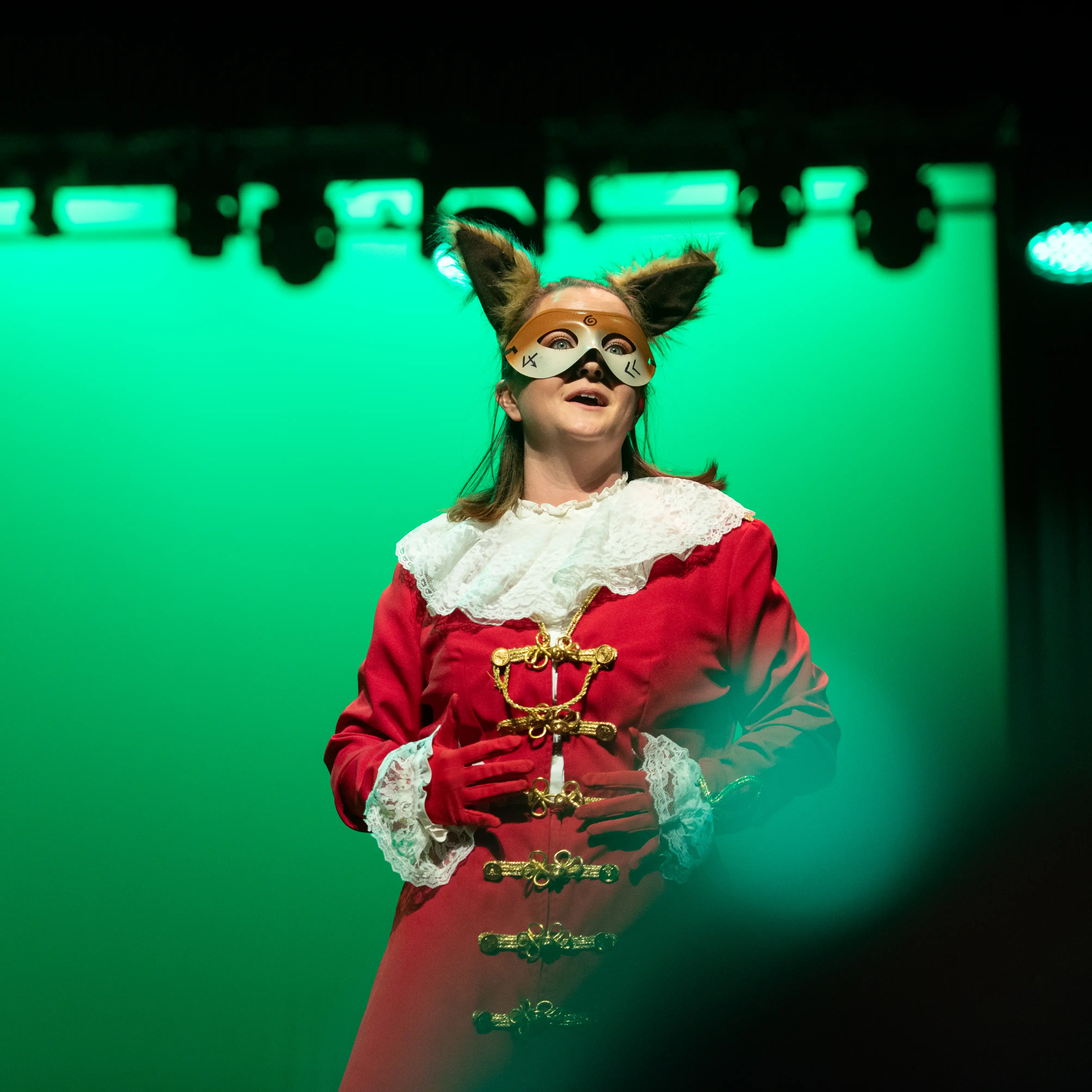 A Belmont University opera student performs onstage in costume under green stage lighting.