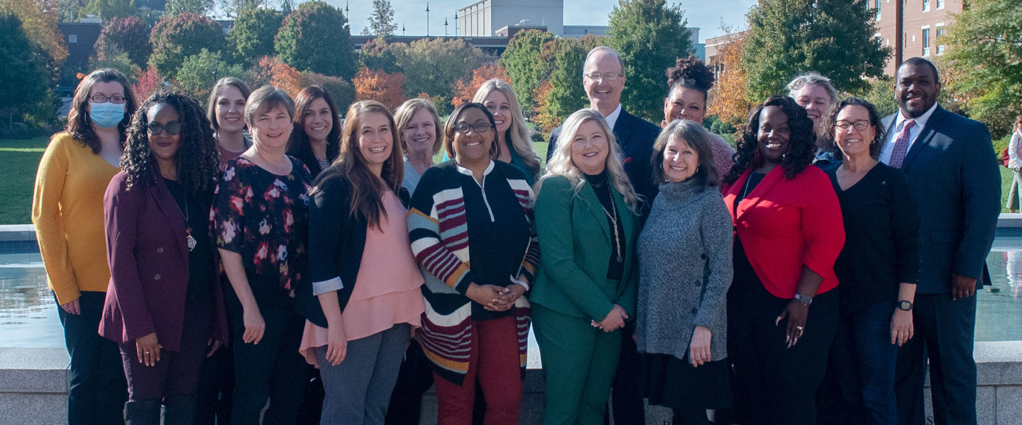 A group of faculty and staff from the College of Education stand in front of the lawn at Belmont University.