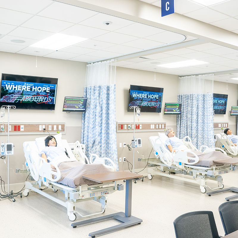 Simulation lab filled with hospital beds and medical dummies for students to practice on