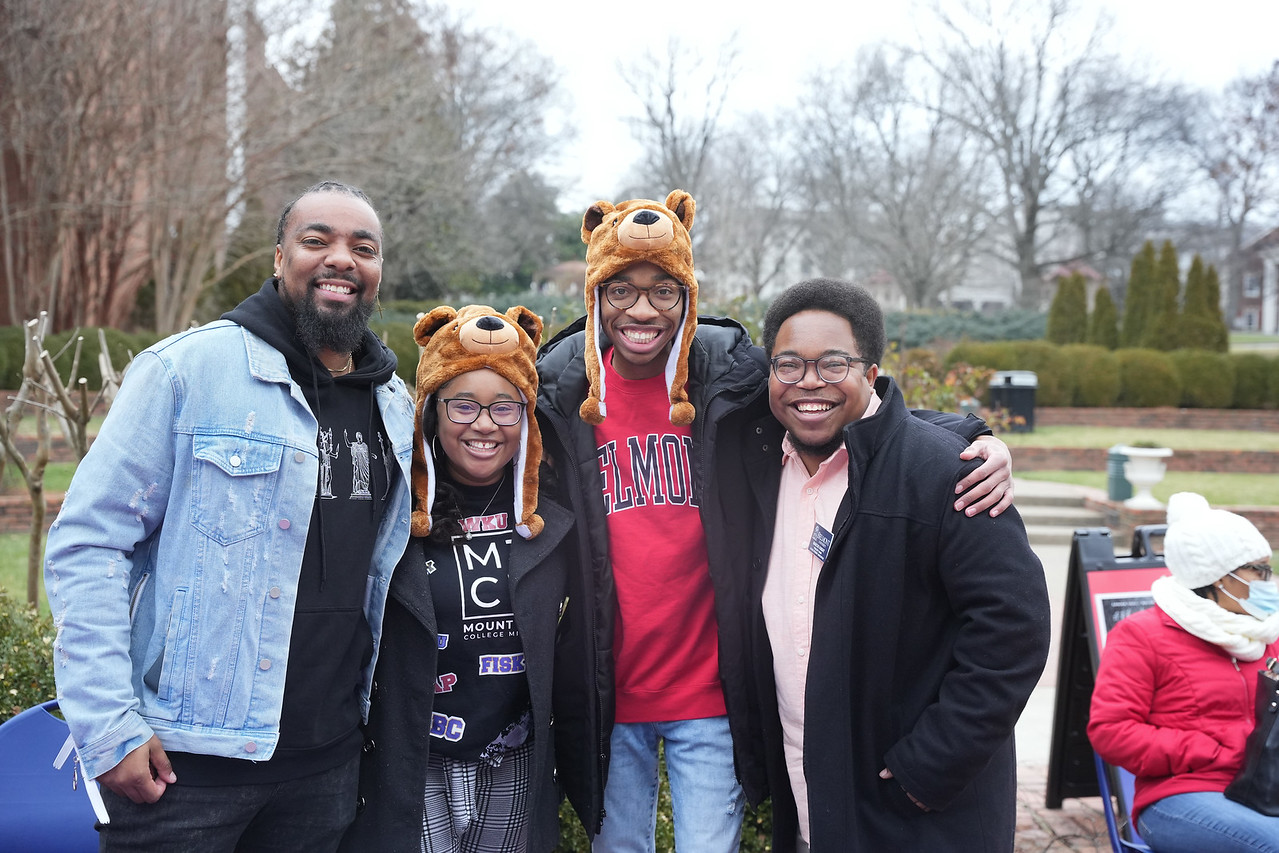 Four students pose for a photo during homecoming with two are wearing bear hats.