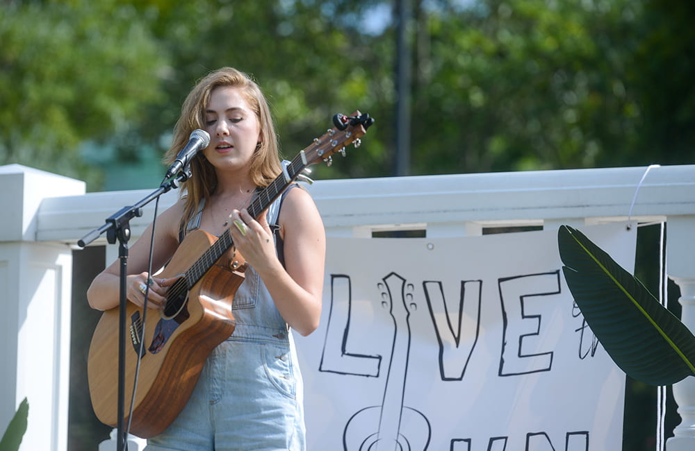 A student playing music on her guitar on the Lawn