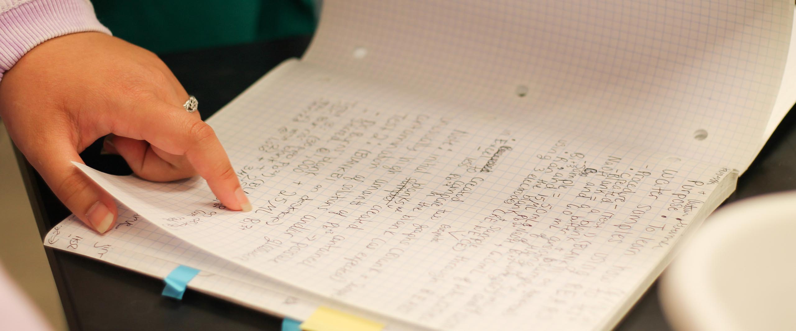 Close up of a hand turning pages of a notebook on a table