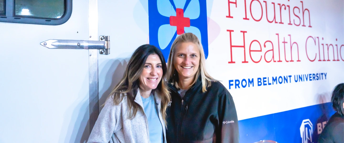 Flourish Health Clinic directors, two smiling women, stand in front of the mobile clinic.