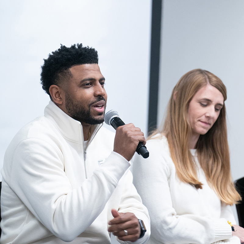 Man talking into mic during panel session during RiseStrong
